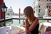 Woman Looking At Menu In Alfresco Cafe