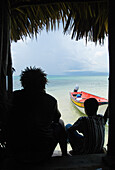 Rasta And Young Boy Sitting In Doorway Of Bar Out At Sea