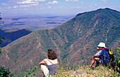 Wanderer sitzen am Rand einer Steilwand mit Blick auf das Samburuland
