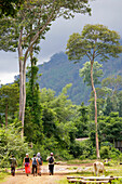 Touristen wandern unter den Bergen auf dem Bolaven Plateau