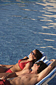 Couple Sunbathing In Swimming Pool.