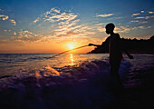 Junge beim Fischen in der Abenddämmerung am Strand neben Kaya Mawa