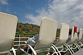 Passagiere entspannen sich auf Sonnenliegen an Bord einer Flusskreuzfahrt