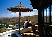Ein Mann sitzt auf einem Balkon mit Blick auf die Felder von Lanzarote.