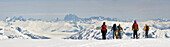 Ein Snowboarder und Skifahrer wandern beim Heliskiing in der Nähe von Juneau, Alaska, entlang des Westgrats des Mt. Hawthorne mit Blick auf das Juneau-Eisfeld und die Teufelskralle