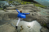 Eine junge Frau springt über eine Pfütze; Skye, Schottland