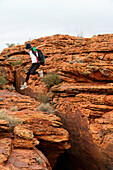 Ein Tourist springt über eine schroffe Felsformation am Kings Canyon; Northern Territory, Australien