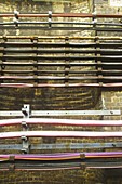 Bündel von Drähten, die in Reihen an einer Steinmauer aufgehängt sind; London, England