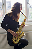 Saxophon spielendes Mädchen in Schuluniform; England