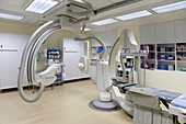 Ein modernes Krankenhauszimmer, eine große tragbare mobile Scannermaschine mit gekrümmten Armen, ein mobiler Scanner und eine Krankenhausliege oder ein Krankenhausbett.