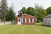Ländliches US-Postgebäude mit wehender amerikanischer Flagge.