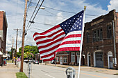 American flag fluttering in the breeze on a deserted main street.