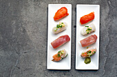 A sushi platter with fresh fish and rice arranged carefully on the dish with garnishes. 