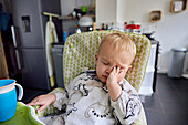 Toddler reaching up and touching appliance in kitchen