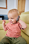 Toddler holding smart phone with animated expression indoors