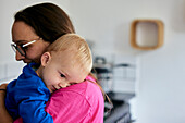 Toddler resting head on shoulder of mother