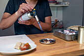 Ein Koch bereitet in einem Restaurant italienische Gerichte zu. Er verwendet einen Schweißbrenner, um ein Gericht zu erhitzen.