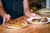 Ein Mann, der an einer Restauranttheke steht und Teller mit gekochten Speisen präsentiert, Menü.