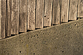 Planks of a wooden fence and concrete wall.