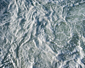 The surface of churning ocean water, overhead view.