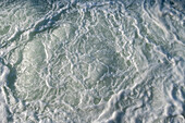 The surface of churning ocean water, overhead view.