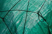 Close up of a tarpaulin cover with folds and ropes. 