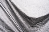 Black and white image, folds of tarpaulin draped across objects. 