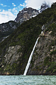 Wasserfall von der Seite eines Berges in einen See; Natales, Magallanes und Antartica Chilena Region, Chile