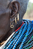Afrika, Äthiopien, Südliches Omo-Tal, Stamm der Nyangatom. Eine ältere Nyangton-Frau mit vier Ohrpiercings und blauen Perlen.