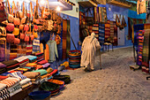 Marokko. Ein älterer Mann geht in einer Straße in der blauen Stadt Chefchaouen an Touristenläden vorbei.