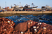 Morocco. Fish nets, floats, boats, and commercial fishing vessels of the harbor in Essaouira.