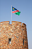 Africa, Namibia, Etosha National Park. Namibian flag flies over brick tower at park entrance