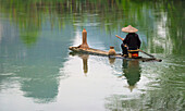 Fischer auf Bambusfloß auf dem Mingshi-Fluss mit Karsthügeln, Mingshi, Provinz Guangxi, China