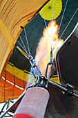 Turkey, Anatolia, Cappadocia, Goreme. Inside of hot air balloon flying above rock formations and field landscapes in the Red Valley, Goreme National Park, UNESCO World Heritage Site. Visual flame heating up balloon.