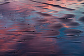 Sonnenspiegelung im schwarzen Sand am Berg Vestrahorn im Winter in der Nähe von Hofn, Island (Großformat verfügbar)