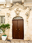 Italy, Puglia, Brindisi, Itria Valley, Ostuni. Old wooden door with ornate carvings surrounding the entrance in old town Ostuni.