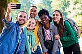 Happy friends taking selfie with smartphone in public park