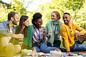 Lächelnde junge Freunde, die zusammen in einem öffentlichen Park sitzen