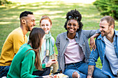 Glückliche junge Freunde beim Picknick im öffentlichen Park