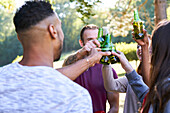 Young friends drinking beer while standing in park