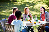 Lächelnde junge Freunde genießen das Essen im Park