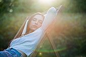 Young woman sleeping on chair in park