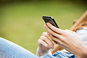 Mid section of young woman using smartphone in park