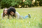 Lächelnde junge Freundinnen im Park liegend