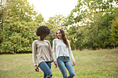 Lächelnde junge Freundinnen gehen im Park spazieren