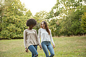 Smiling young female friends walking in park