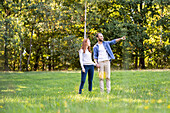 Smiling young man pointing something to his partner while standing in park