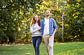 Smiling young couple having fun while walking in park
