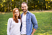 Porträt eines lächelnden jungen Paares bei einem Spaziergang im Park