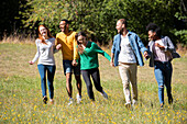 Glückliche junge Freunde, die zusammen in einem öffentlichen Park spazieren gehen